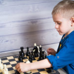 cute-little-blonde-boy-is-making-his-move-while-playing-chess-logic-developing-board-game_116317-1685